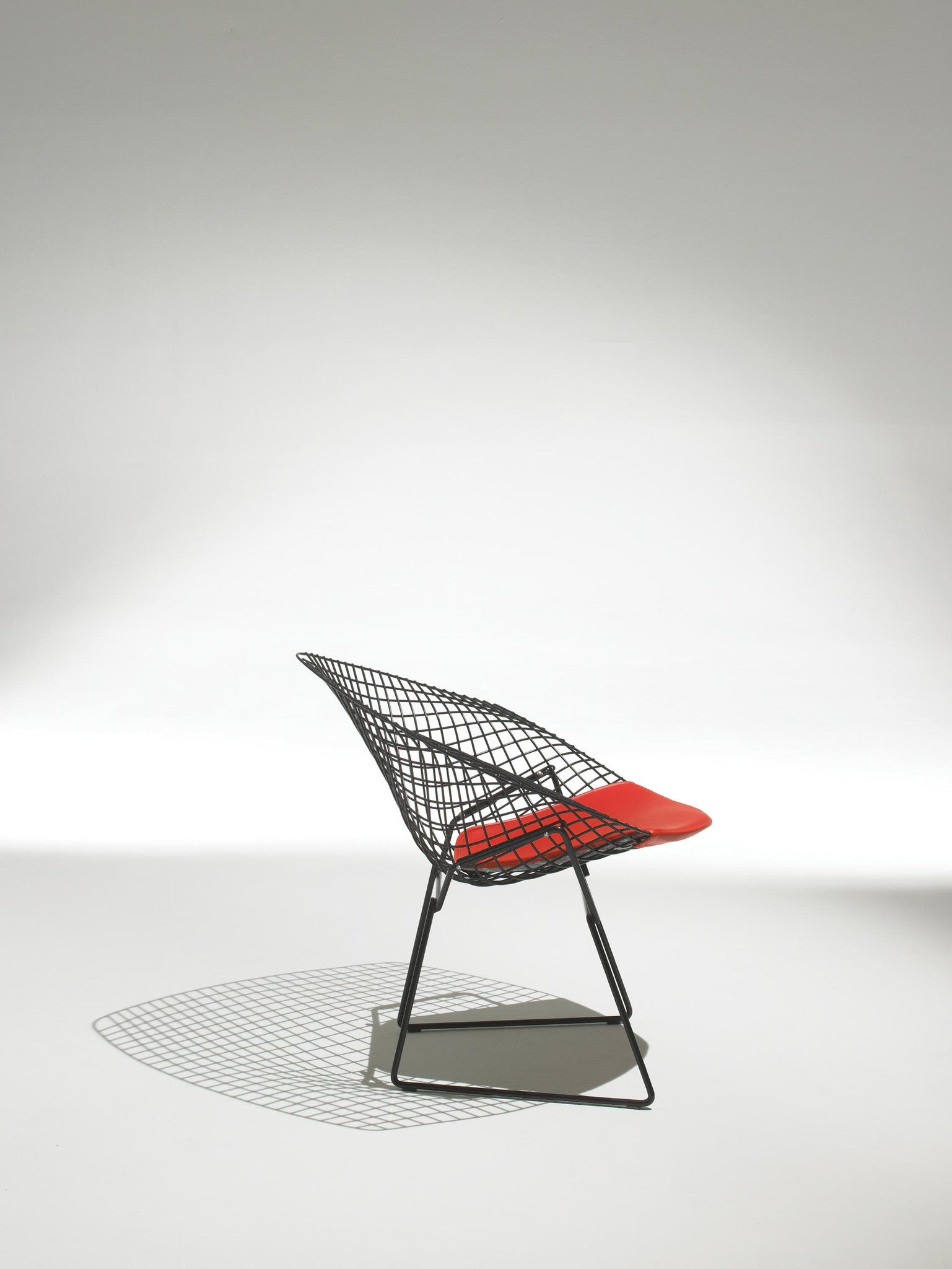 Bertoia Diamond Armchair side view orange cushion